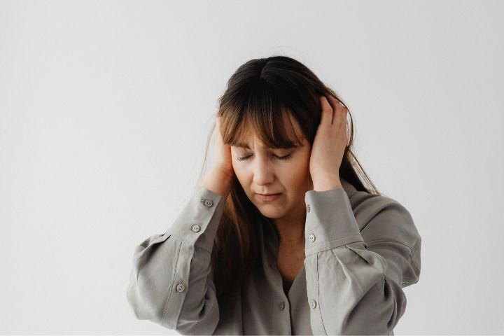 Woman in Gray Long Sleeves with Eyes Closed and Hands on her Ears