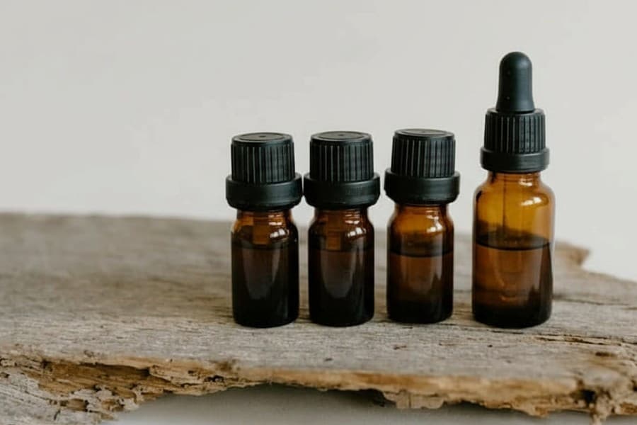 Illustration of four natural botanical oils sitting on a wooden surface, showing a simple ritual for nail and skin support